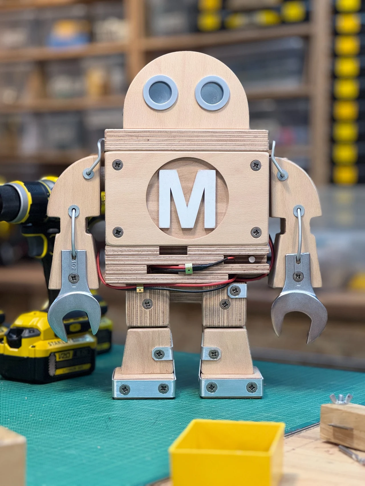 Frontansicht der Makey-Figur aus Holz mit Metallaugen, Drahtverbindungen und Schraubenschlüsseln als Händen