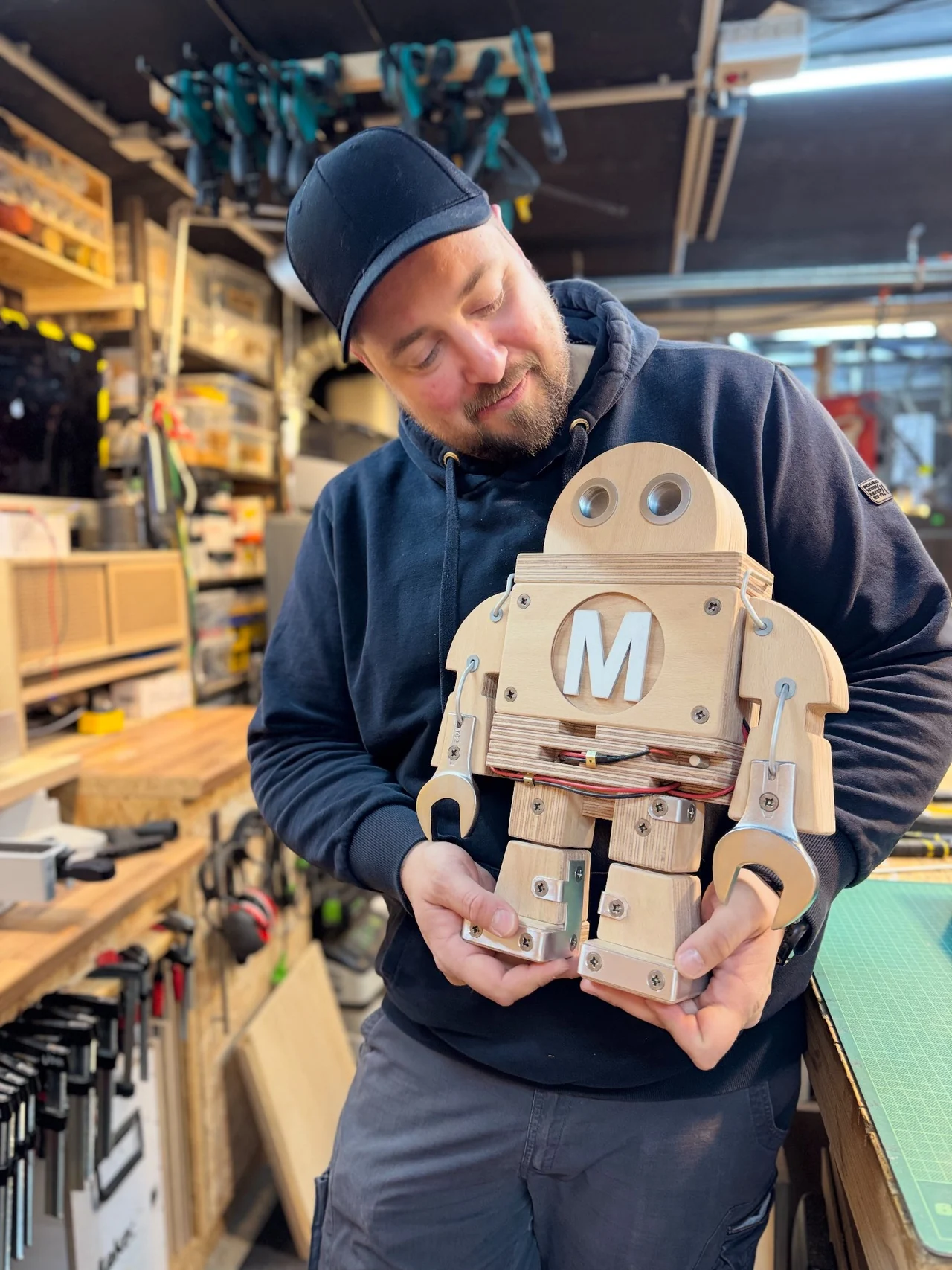 Eine Person hält die fertige Makey-Figur in der Werkstatt in beiden Händen