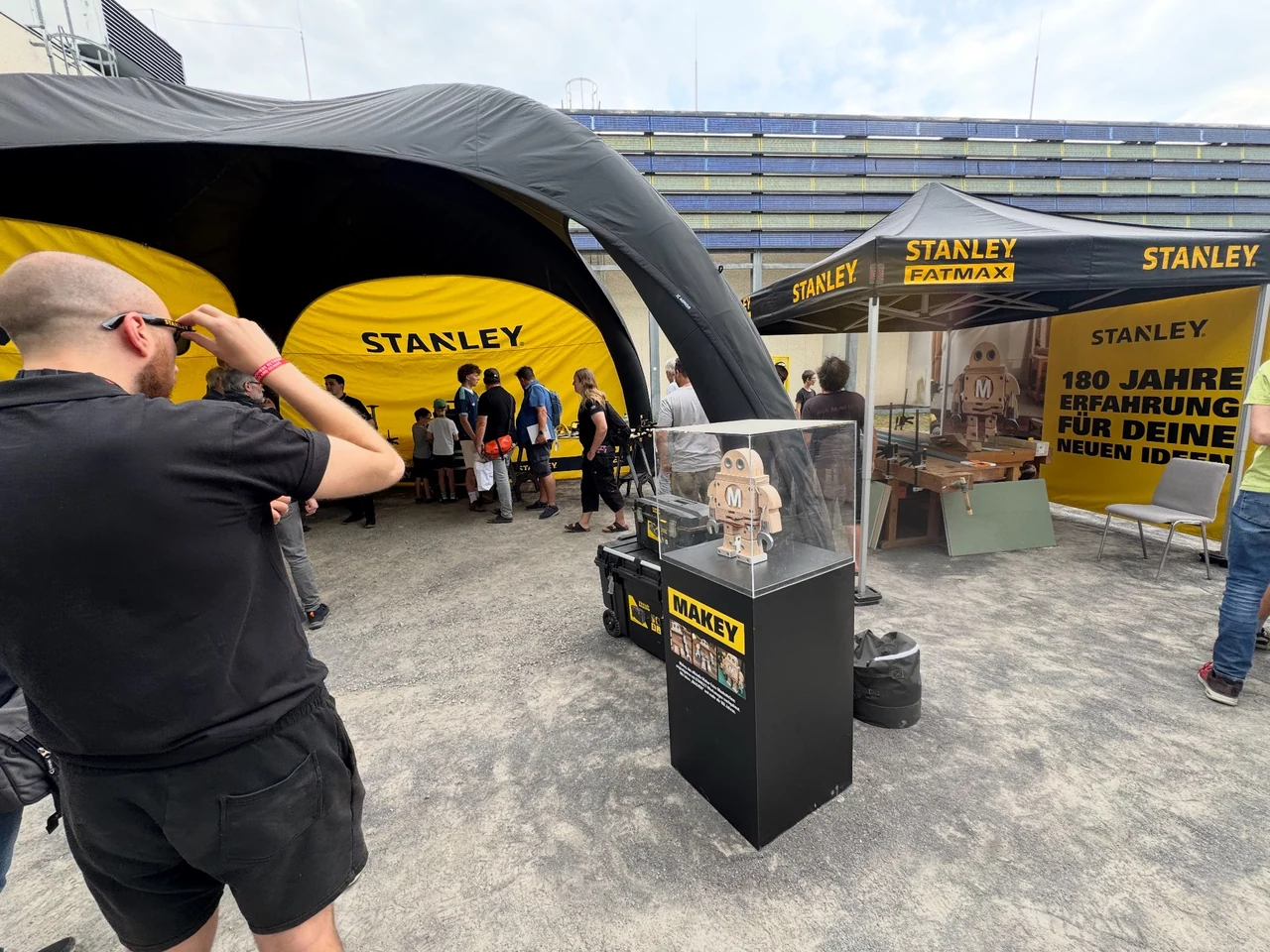 Stanley-Messestand auf der Maker Faire mit Besuchern, Makey in einer Vitrine und einem großformatigen Motiv der Figur