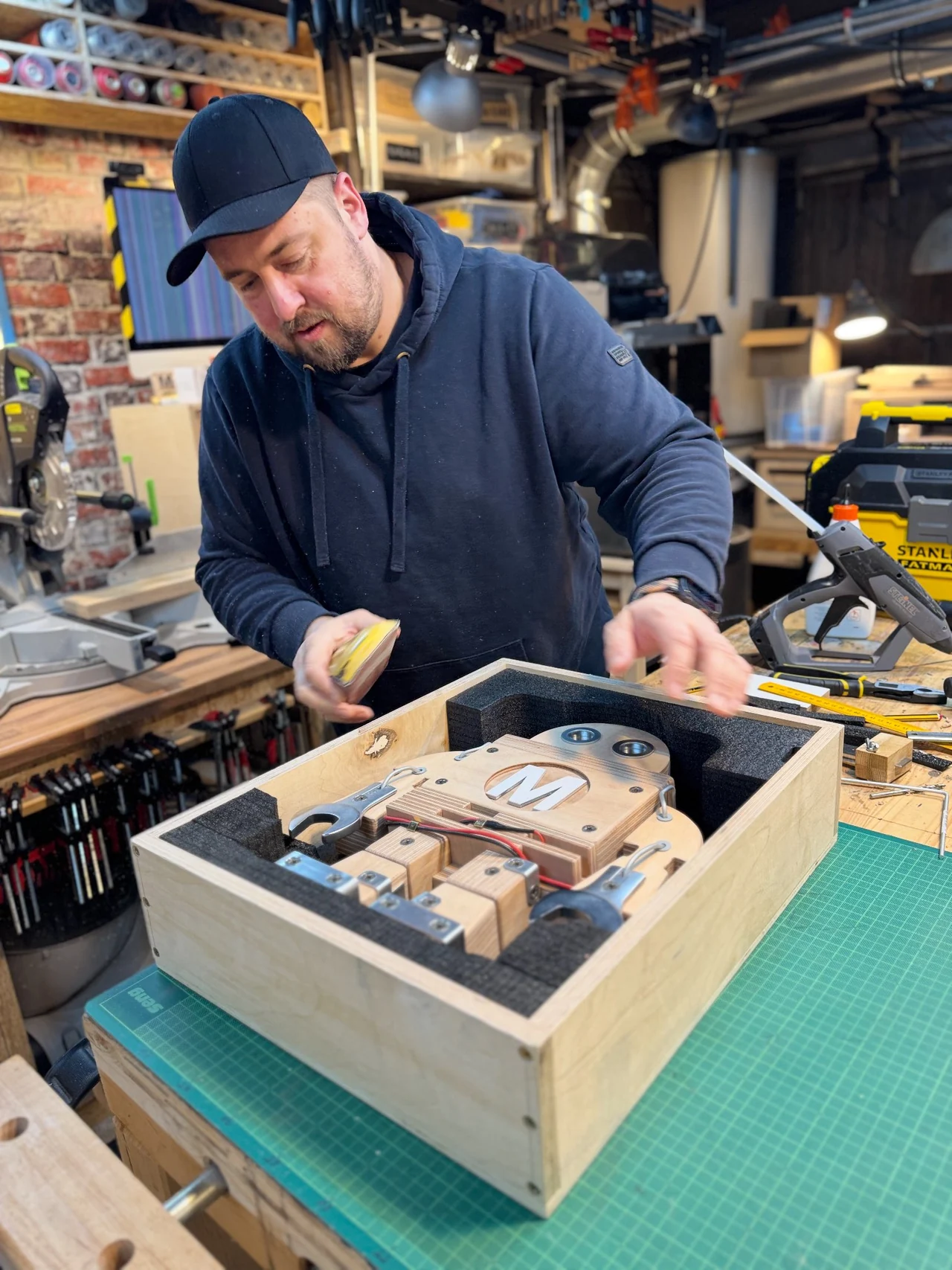 Makey in einer mit Schaumstoff ausgepolsterten Holzkiste auf der Werkbank