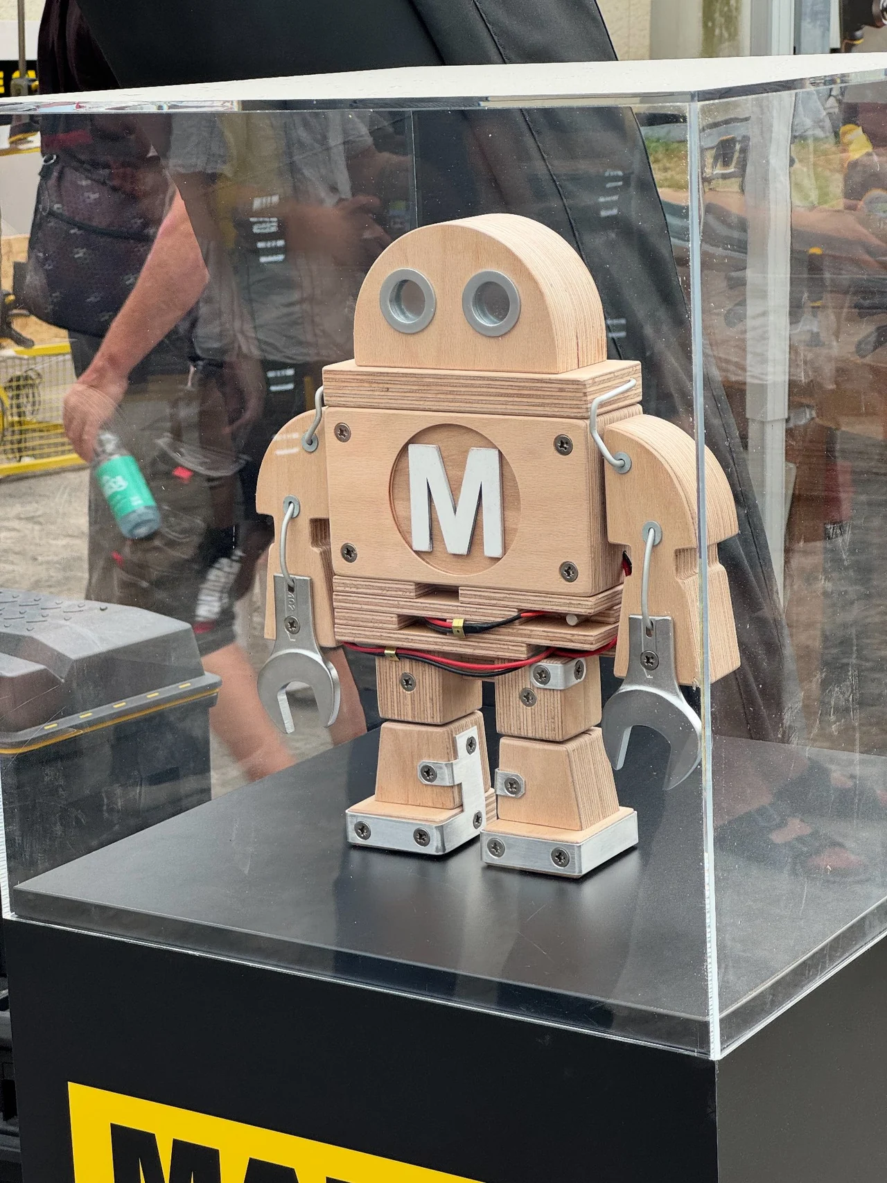 Makey aus Holz und Werkzeugteilen unter einer transparenten Schutzhaube auf einem schwarzen Ausstellungssockel